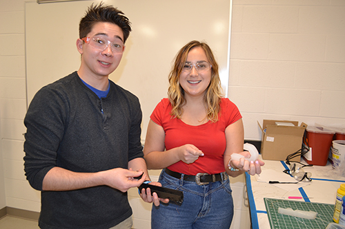 Kyle Ritchie (left) exhibits the mold he designed, while Stephanie Zimbru demonstrates a prototype of their flex tip catheter.