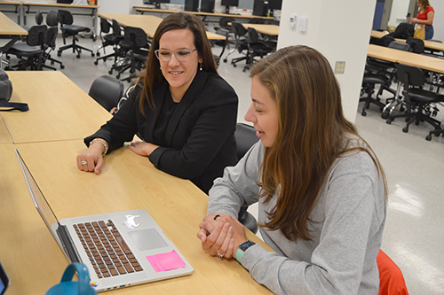 A BioE435 student shows Holly Golecki (left) an image of the covered equine uterine swab she and her teammates are designing.