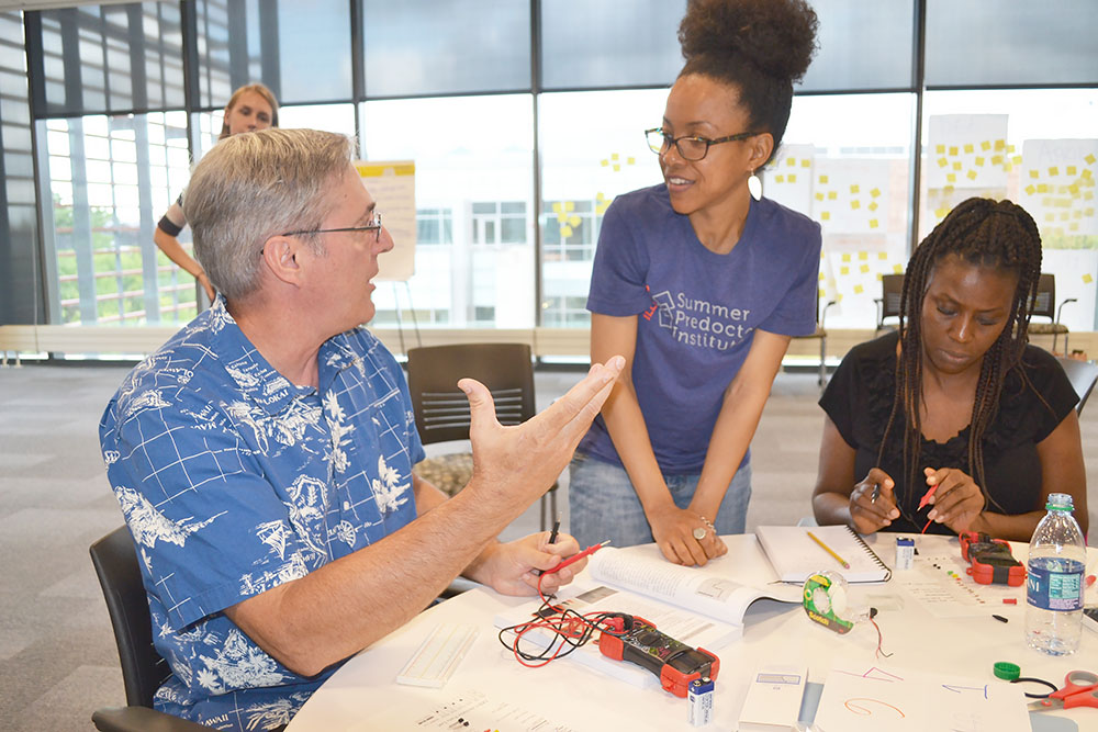 Mahomet-Seymour High chemistry teacher Terry Koker chats with Goddard's PhD student and long-time GLEE camp assistant, Lonna Edwards, about the circuit he's building.