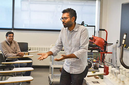 Arijit Banerjee (left) listens while Subhonmesh Bose teaches the educators about his research about power.