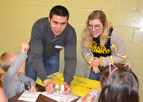 Two Illinois students do an activity with young visitors during Cena y Ciencias