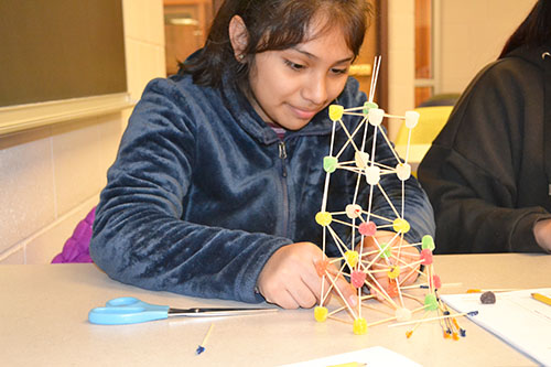 A ChiS&E seventh grader works on her team's toothpick-gumdrop structure.