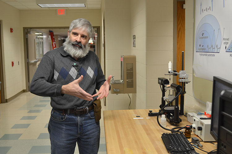 MRL senior research scientist Julio Soares demonstrates to STEAM Academy eighth graders how the contact angle goniometer analyzes the shape of drops of liquid. 