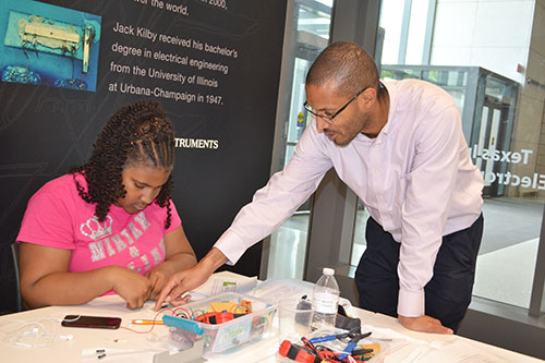 Lynford Goddard (right) helps Cheyenne McClinton with her LED calculator.