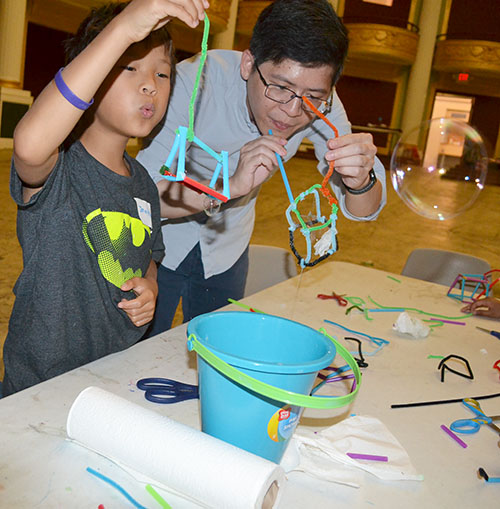 Jie Feng (right) and a boy at the Orpheum outreach blow bubbles throught the 3D wands they  created.