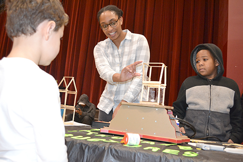 Jamie Clark, a member of the  GEDI organization, tests the  earthquade structure a young visitor built.