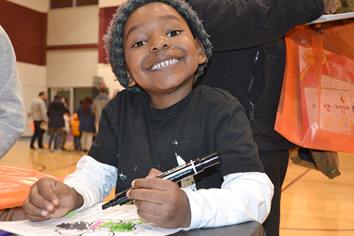 A STEAM night visitor is all smiles while working at the Anamorphic Art Station.