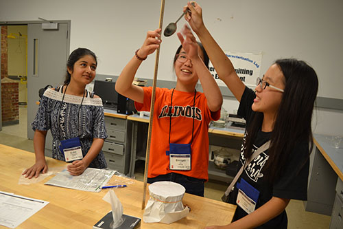 A team of campers test the strength of freezer paper by dropping a spoon on it. They found it to be the strongest of the various materials