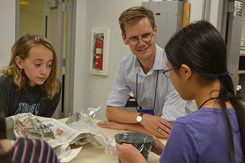 Robert Maass (center) interacts with a team of campers testing various materials during the spoon drop activity.