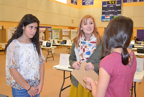 Taylor Braastad (center) listens as two NGS students present their research.