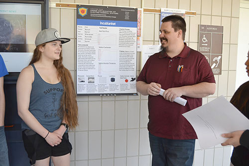 Albert Pattinson (right), a PHD candidate in ISE (Industrial Systems and Engineering), interacts with students presenting their research.