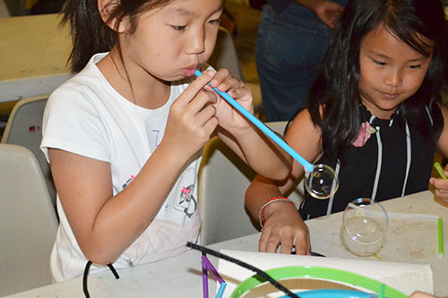 A youngster at the Orpheum employs a straw to blow some bubbles.