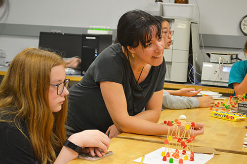 Ceclia Leal (center) ejoys watching a team's toothpick/gumdrop structure being tested.