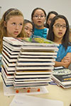 A team of Mid-GLAM campers test the toothpick/gumdrop structure they built by stacking academic journals onto it.