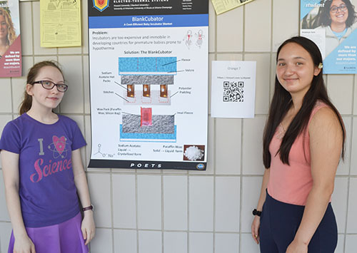 Uni High students Katie Powers and Lauren Mettlett by  their poster.