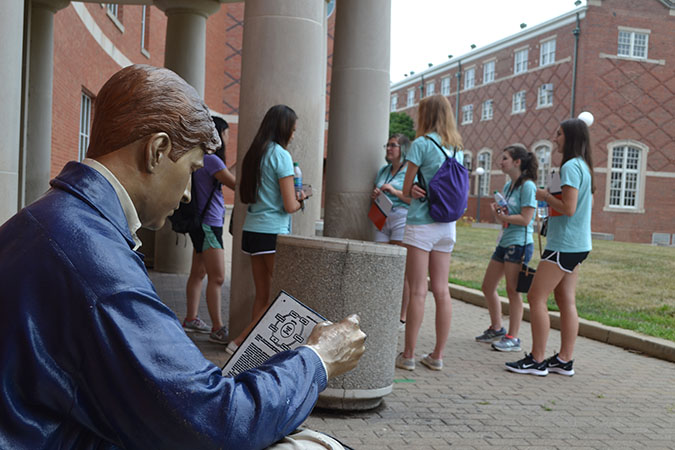 At the fall 2019 WIE Orientation, a group of female engineering freshmen chat on the south portico of Grainger Library as Grainger Bob looks on.