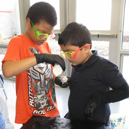 Urbana Middle School student helps BTW student during a hands-on project were students used polymers to make their own rubber ball.