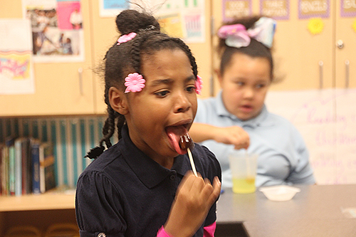 A BTW fourth grader conducts research to determine the degree of corrosive wear licking will have on her lollipop. (Photo courtesy of Joe Muskin.)