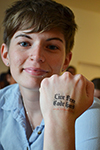 A Blue Waters intern displays the tatoo she got during a tour of the Petascale facility. The message: Live free; code hard