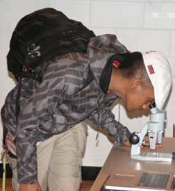 Student examines algae at BioMath poster presentation.