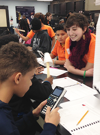  Clockwise from the right: An <em>Illinois</em> student looks on as a young Chicago student uses a graphing calculator. (photo by Sahid Rosado)