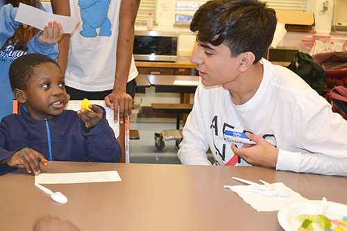 A Uni High student (right) watches as a local boy from the DREAAM House program tastes fruit during an activity.