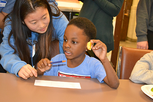 A Uni High volunteer (left) watches a DREAAM House youngster taste an orange to determine whether it tastes sweeter.