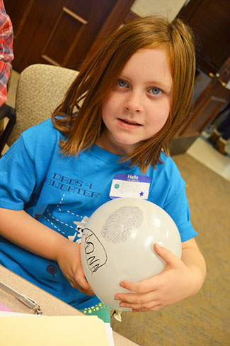 A young participant shows the fingerprint balloon she made.