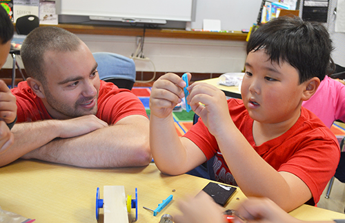 George Popovic (left) helping a student build his solar car.