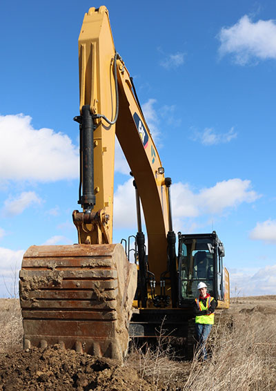Dylan Taylor by a Cat Excavator at Duininck, a Minnesota construction company.