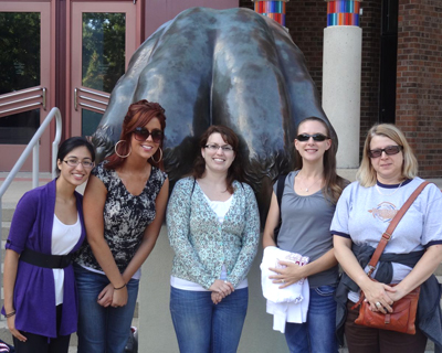 Asha Kirchoff, Christine Littrell,Jenny Amos, Jenny Ernthaller, and Marie-Christine Brunet pose by statue of Nitany Lion paw on the Penn State campus.
