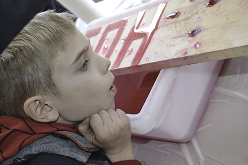 At EOH 18, a local 1st grader learns about the effect of hydrophobic materials as he blows on water, causing it to  bead up on a treated board.