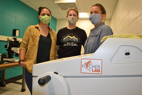 Fischer (right) and her researchers by a large piece of  equipment in her lab.