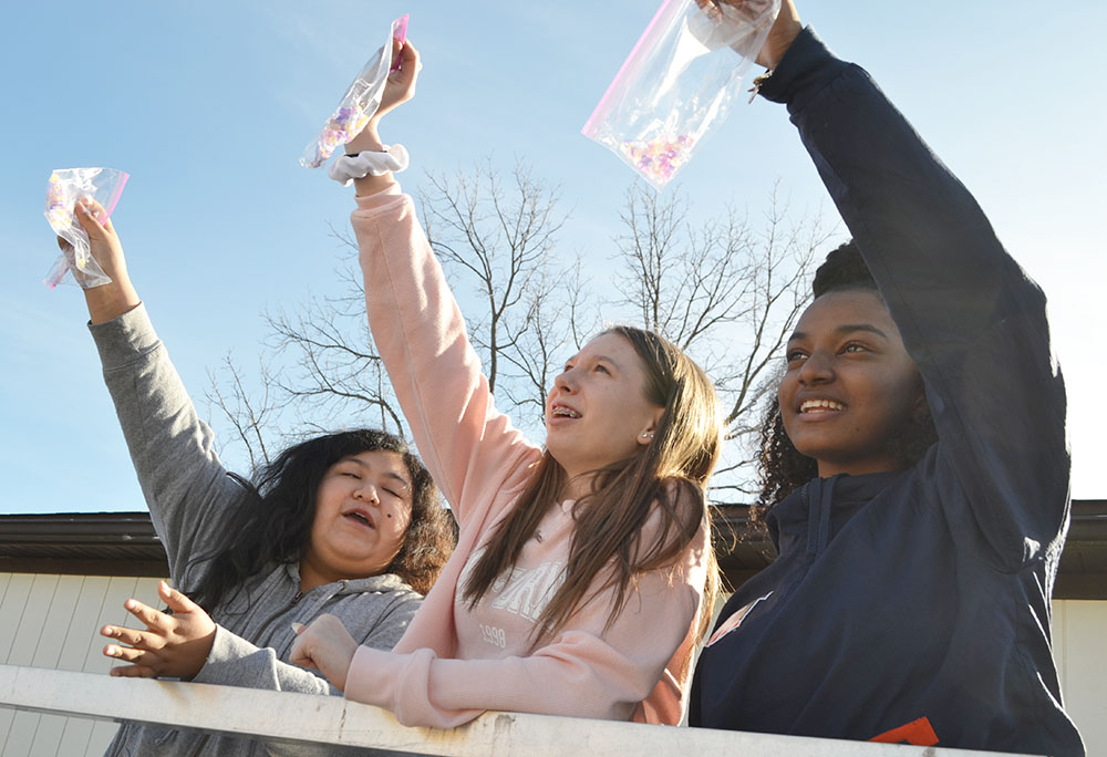 Franklin seventh graders show off the necklaces they’ve made from special beads that react to UV light.