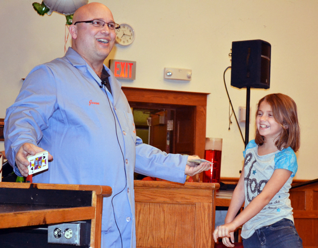 Jesse Miller performs a card trick with the help of a young volunteer.