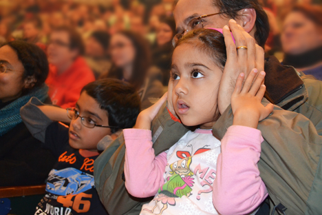 Youngsters cover their ears in anticipation of a balloon full of gas exploding.