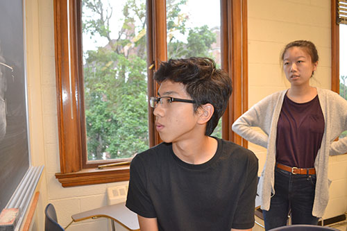 Caption: Weihang Wang (right) watches a Uni student solving a problem.
