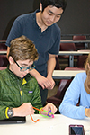 An IGL student (standing) looks upon as Central High students work on creating their knot.