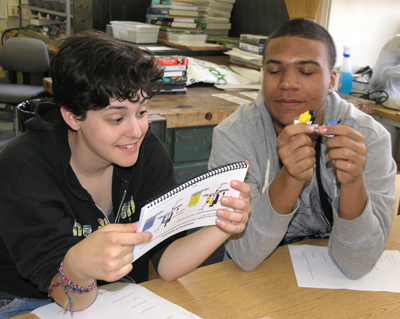 Student reads instructions included with Lego kit while the other follows the directions.