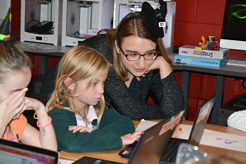 Amy Merkelz helps a young visitor with her design on the computer.