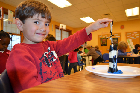 NGS kindergartener proudly points to the second story of his structure, which withstood the box fan test.