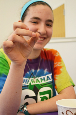 NGS student Lia Dankowitz shows how the strand has reverted to its "memorized" state (straight) after being placed in hot water.