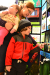 A mother and her son examine a display about "Creatures That Are Not Afraid of the Dark," while her daughter considers her career options.