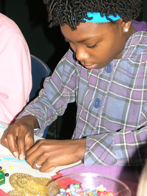 Heritage School student using beads to learn about bee anatomy.