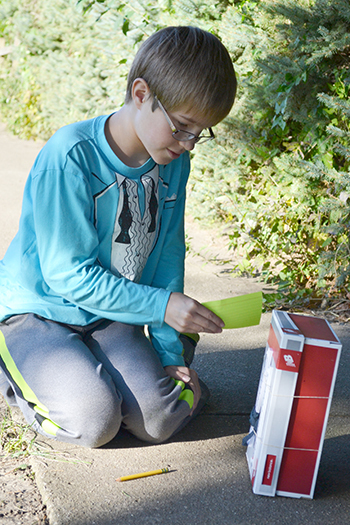 STEAM studio student waves a piece of paper to cool down his sling psychrometer.