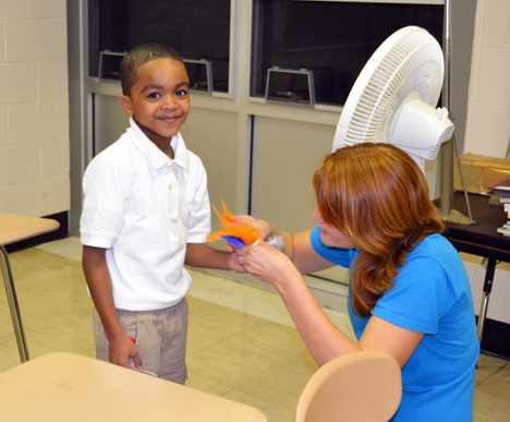 A Danville youngster gets assistance from an Illinois student as he prepares to test the "seed" he designed in front of a box fan to see if can be blown by wind, similar to seeds that use that mode of transportation.