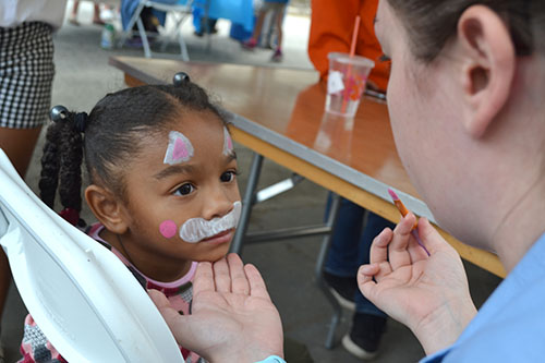 Vet Med student Aiden Tansey paints the face of young visitor.