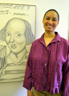 Rebecca Ginsburg poses by a poster of the EJP Shakespeare class's presentation of The Tempest.