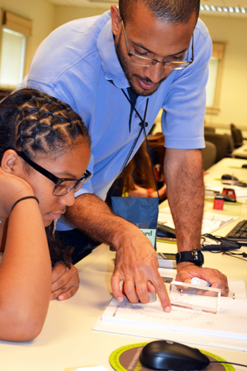In a 2013 GLEE GAMES camp, Lynford Goddard gives a camper some one-on-one instruction during a session on optics.