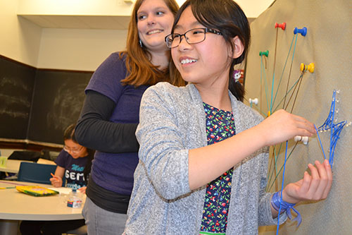 Emily Heath (left), AWM’s Outreach Chair, working with a GEMS participant during the string art workshop.